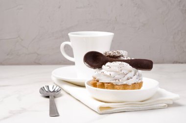 Sütlü beyaz proteinli kek sepeti beyaz bir tabakta çikolata kaşığı ve bir fincan kahveyle süslenmiş. Tatlı teması. 