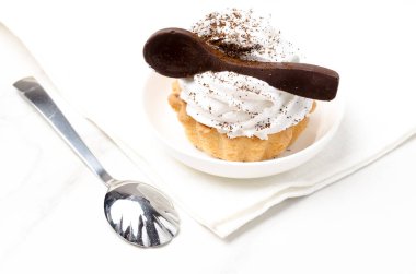 Süslü beyaz proteinli kek sepeti beyaz bir tabakta beyaz bir çikolata kaşığıyla süslenmiş..