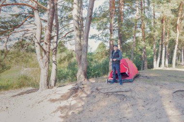 Adam ormanda çadırın yanında oturuyor. Açık hava kampı.