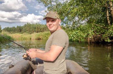 Elinde değnekle kayıktaki genç bir adamın portresi. Güneşli bir gün.