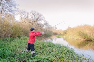 Balıkçı sporcu, oltayı nehre atıyor. Spor balıkçılığı.