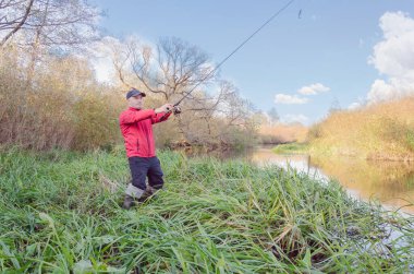 Balıkçı sporcu, oltayı nehre atıyor. Spor balıkçılığı.