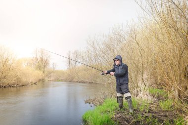 Balıkçı, nehrin üzerinde duran bir oltayla bir balık çeker. Erkek hobisi.