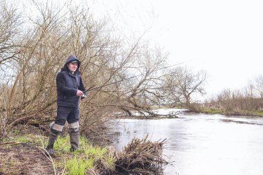 Balıkçı, nehrin üzerinde duran bir oltayla bir balık çeker. Erkek hobisi.