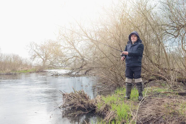 Nehir kıyısında elinde olta olan bir balıkçı. Doğadaki hobi.