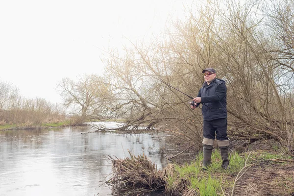 Nehrin kıyısında yağmurda balık tutan bir adam.. 
