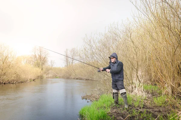 Balıkçı, nehrin üzerinde duran bir oltayla bir balık çeker. Erkek hobisi.