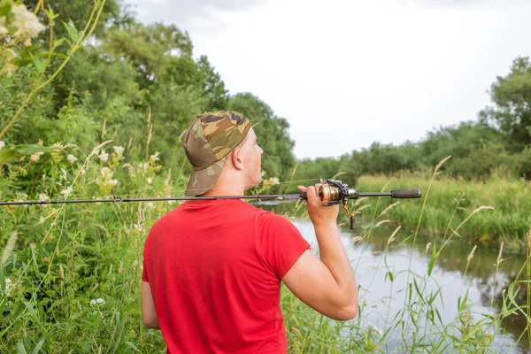 Elinde olta olan bir balıkçı. Arkadan bak..