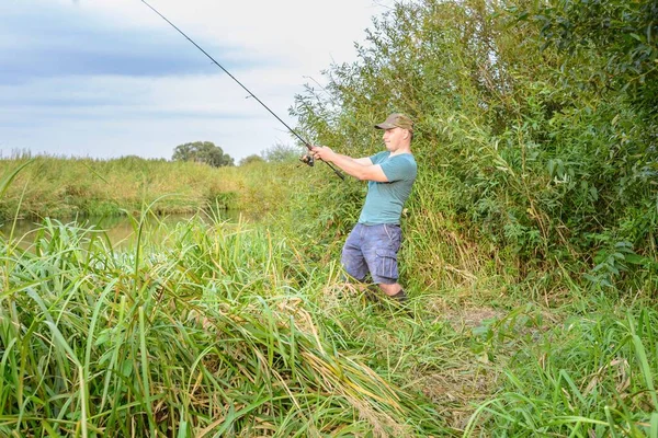 Nehir kıyısında elinde olta olan yakışıklı bir genç. Açık hava sporları.
