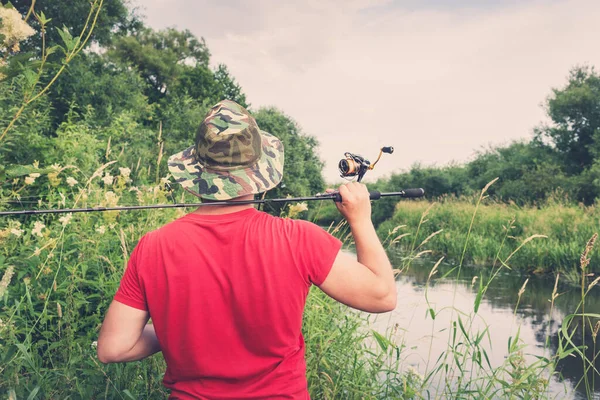 Elinde olta olan bir balıkçı. Arkadan bak..
