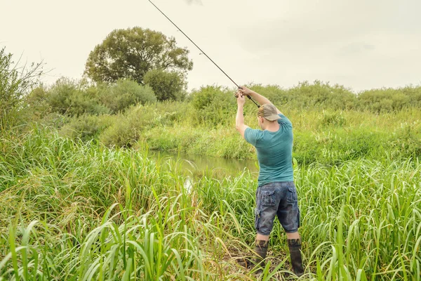 Yakışıklı genç adam nehir kıyısına bir döner çubuk fırlatıyor. Doğadaki hobi.