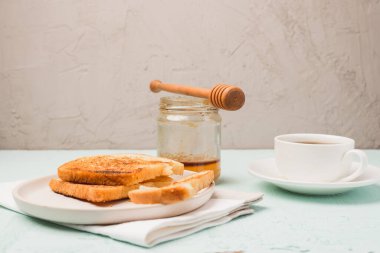 Tabakta tost, bal kavanozunda kaşık ve fincanda kahve. Kahvaltı hala hayattadır..