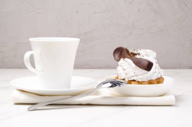 Sütlü beyaz proteinli kek sepeti beyaz bir tabakta çikolata kaşığı ve bir fincan kahveyle süslenmiş. Tatlı teması. 