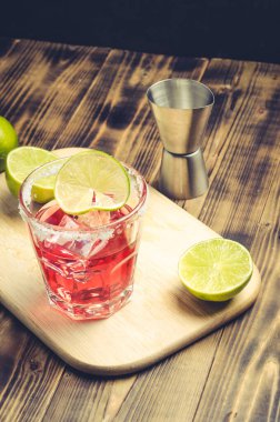 Ahşap bir masada limonlu kırmızı kokteyl. Kavram çubuğu.