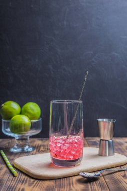 Kırmızı içeceği bardakta buzla karıştırmak. Karanlık bir arka planda kokteyl hazırlıyorum..