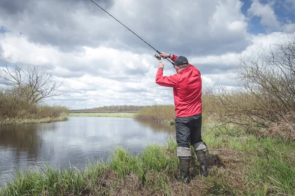 赤い上着を着た漁師が川の緑の岸で釣りをしている 美しい風景 — ストック写真