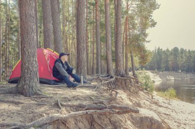 Çadırın yanındaki genç adam, elinde fotoğraf makinesiyle güzel bir manzara..