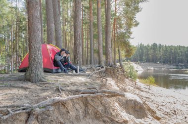 Çadırın yanındaki genç adam, elinde fotoğraf makinesiyle güzel bir manzara..