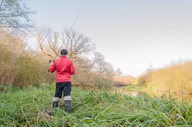 Balıkçı nehre bir olta atar. Arkadan bak.. 