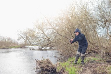 Balıkçı, nehrin üzerinde duran bir oltayla bir balık çeker. Erkek hobisi.