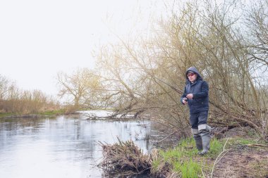 Balıkçı, nehrin üzerinde duran bir oltayla bir balık çeker. Erkek hobisi.