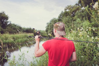 Elinde olta olan bir balıkçı. Arkadan bak..