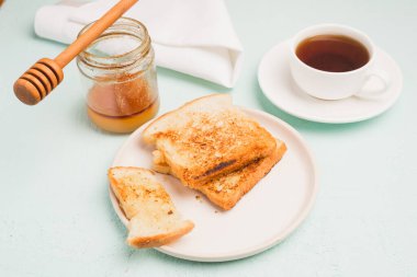 Tabakta tost, bal kavanozunda kaşık ve fincanda kahve. Kahvaltı hala hayattadır..