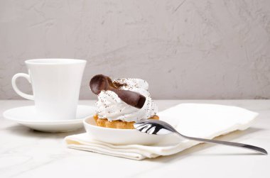 Sütlü beyaz proteinli kek sepeti beyaz bir tabakta çikolata kaşığı ve bir fincan kahveyle süslenmiş. Tatlı teması. 