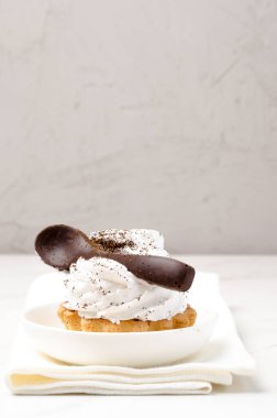 Süslü beyaz proteinli kek sepeti beyaz bir tabakta beyaz bir çikolata kaşığıyla süslenmiş..