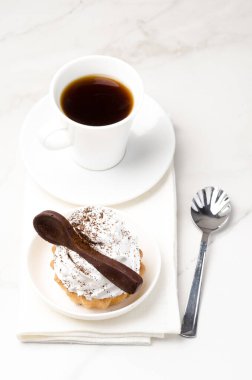 Süslü beyaz protein kremalı kek sepeti beyaz bir tabakta beyaz bir çikolata kaşığıyla süslenmiş. Üst görünüm.