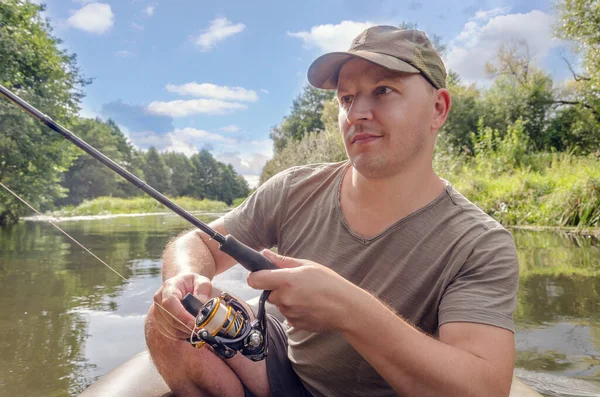 Portrait of a young man in a boat with a spinning rod.