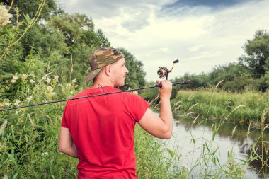 Elinde olta olan bir balıkçı. Arkadan bak..