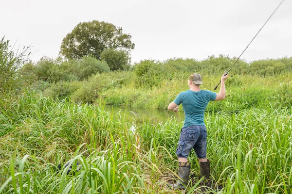 Yakışıklı genç adam nehir kıyısına bir döner çubuk fırlatıyor. Doğadaki hobi.