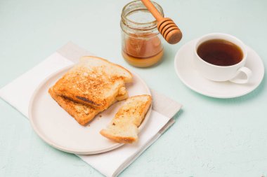 Tabakta tost, bal kavanozunda kaşık ve fincanda kahve. Kahvaltı hala hayattadır. Üst görünüm