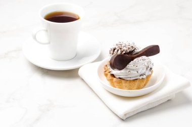 Sütlü beyaz proteinli kek sepeti beyaz bir tabakta çikolata kaşığı ve bir fincan kahveyle süslenmiş. Tatlı teması. 