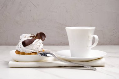 Sütlü beyaz proteinli kek sepeti beyaz bir tabakta çikolata kaşığı ve bir fincan kahveyle süslenmiş. Tatlı teması. 