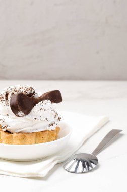 Süslü beyaz proteinli kek sepeti beyaz bir tabakta beyaz bir çikolata kaşığıyla süslenmiş..