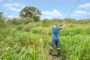 Yakışıklı genç adam nehir kıyısına bir döner çubuk fırlatıyor. Doğadaki hobi.