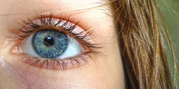 Makroaufnahme eines überraschten Kindes mit blauem Auge und Haaren Stockfoto