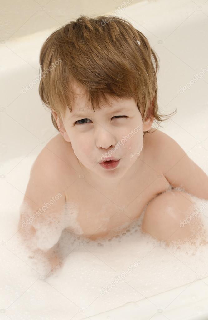 Cunning three years boy in a bathtub with soap foam.