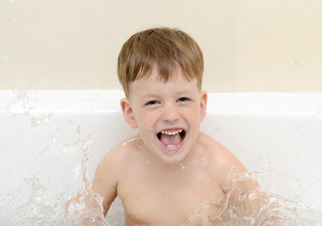 The boy splashes in a bathroom