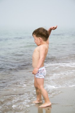 Çocuk taşlar denize atar.