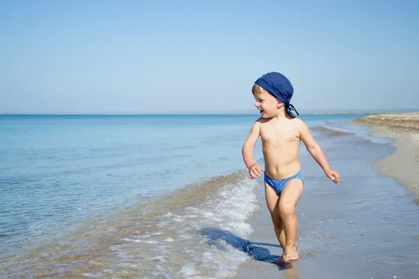 Menino bonito está correndo no mar — Fotografia de Stock