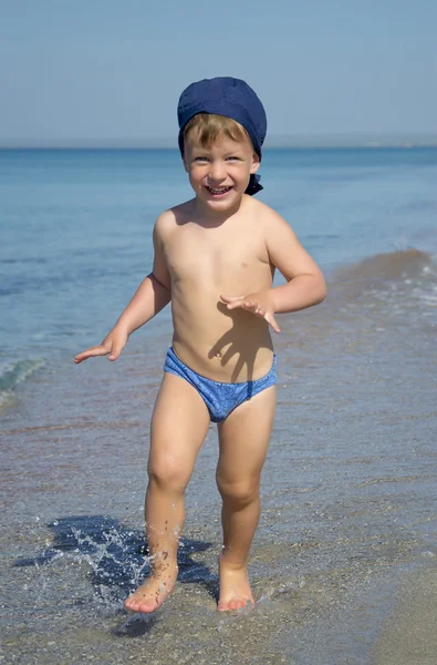 Menino bonito está correndo no mar — Fotografia de Stock