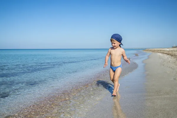 Menino bonito está correndo no mar — Fotografia de Stock