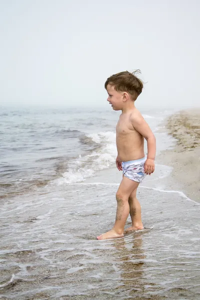 Pojken kastar stenar i havet — Stockfoto