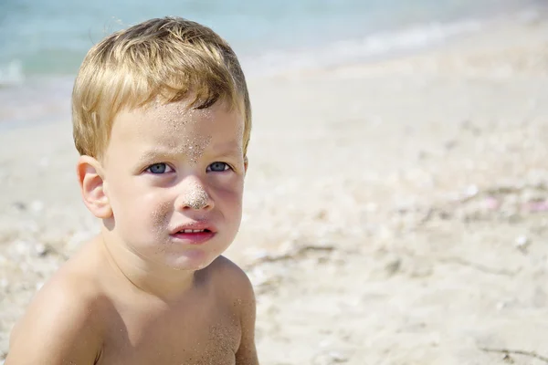 Retrato de menino de três anos na praia, rosto na areia — Fotografia de Stock
