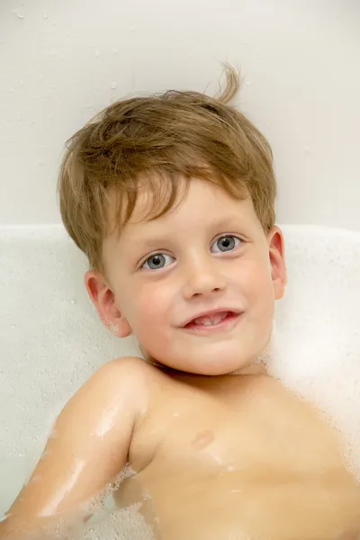 Bonito menino de três anos tomando um banho com espuma — Fotografia de Stock