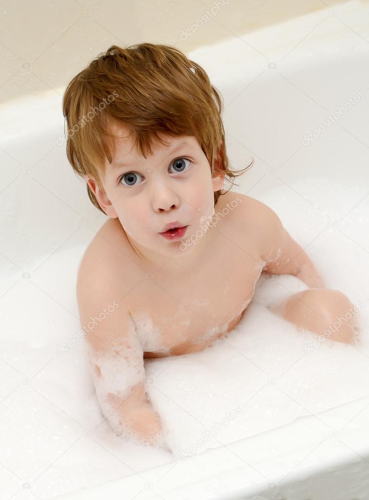 Cute boy taking a bath with foam
