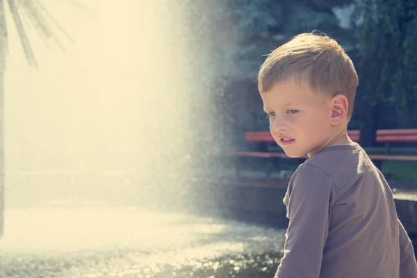 Pojke nära fountaine i sommardag — Stockfoto